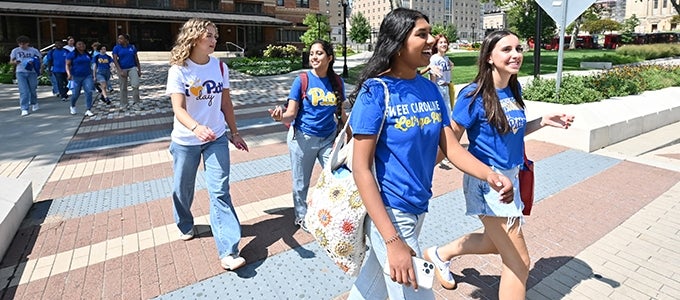 students wearing Pitt t-shirts crossing Bigelow Boulevard toward Cathedral of Learning