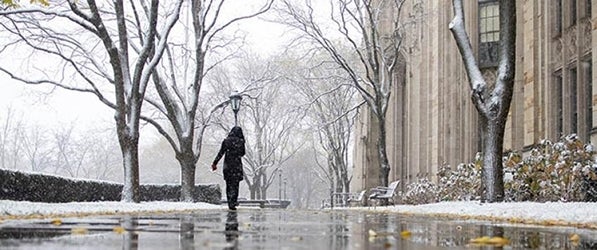 Pitt student walking on snowy campus sidewalks